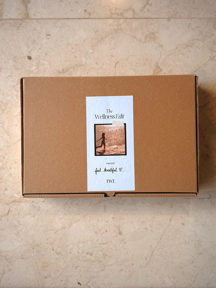 A box with beauty self care essentials such as a handmade wooden gua sha comb to boost circulation and encourage hair health, crystal face gua sha, rose and aloe vera face mist, tinted peptide lip balm and detail card.